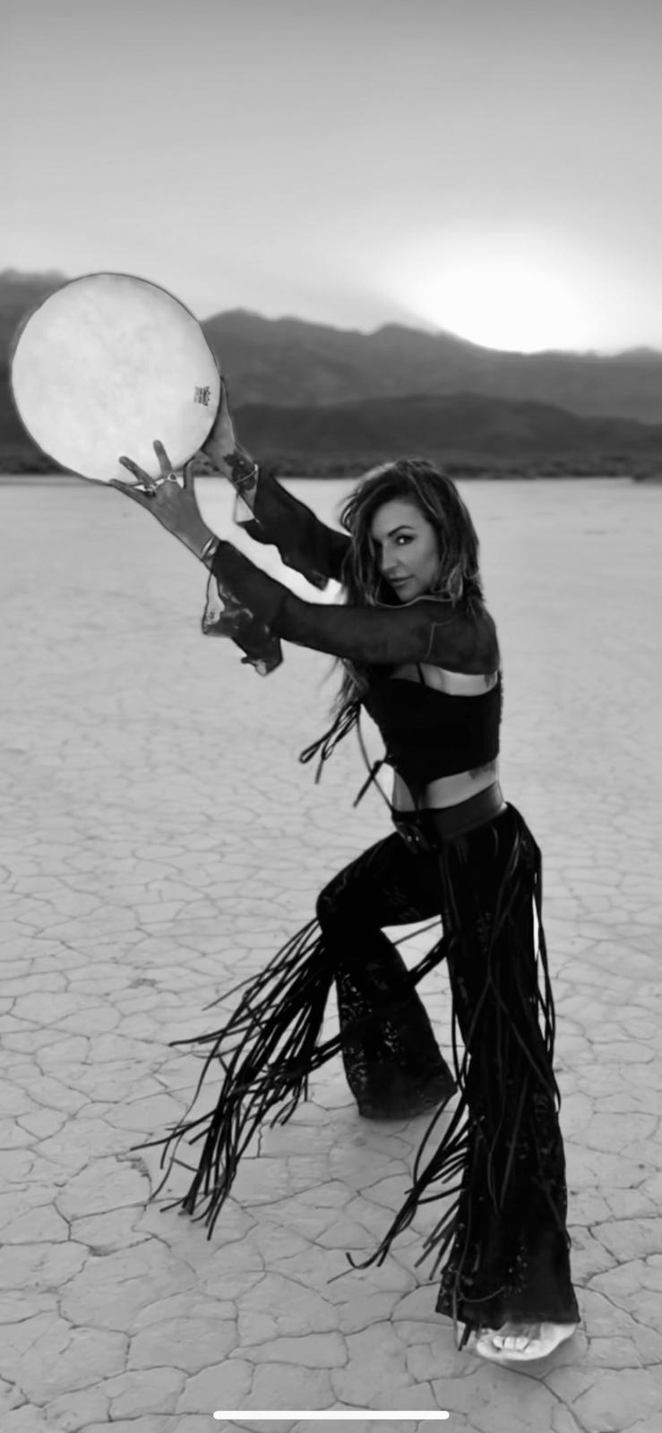 Sara holding a frame drum on the dry lake bed